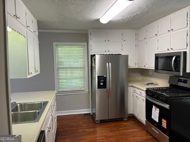 kitchen featuring appliances with stainless steel finishes, a sink, dark wood-style floors, light countertops, and a textured ceiling