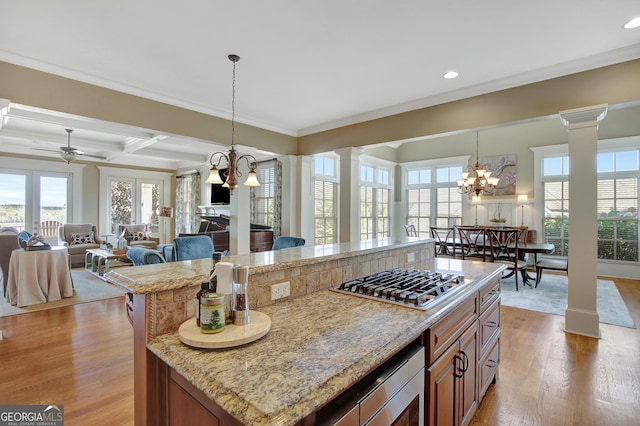 kitchen with decorative columns, appliances with stainless steel finishes, plenty of natural light, brown cabinetry, and recessed lighting