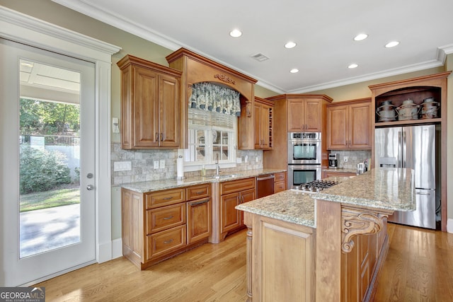 kitchen featuring appliances with stainless steel finishes, a sink, light wood finished floors, a kitchen island, and recessed lighting