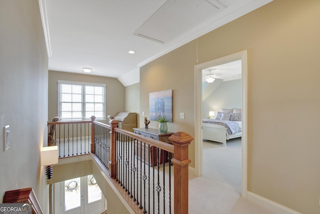 hall with attic access, carpet floors, baseboards, and an upstairs landing