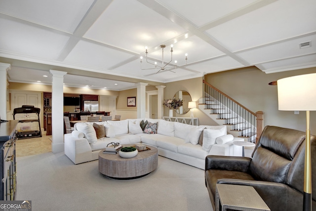 living room featuring ornate columns, coffered ceiling, a chandelier, crown molding, and stairs