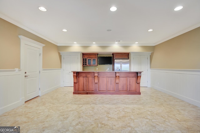 kitchen featuring built in refrigerator, a wainscoted wall, a kitchen breakfast bar, a decorative wall, and ornamental molding