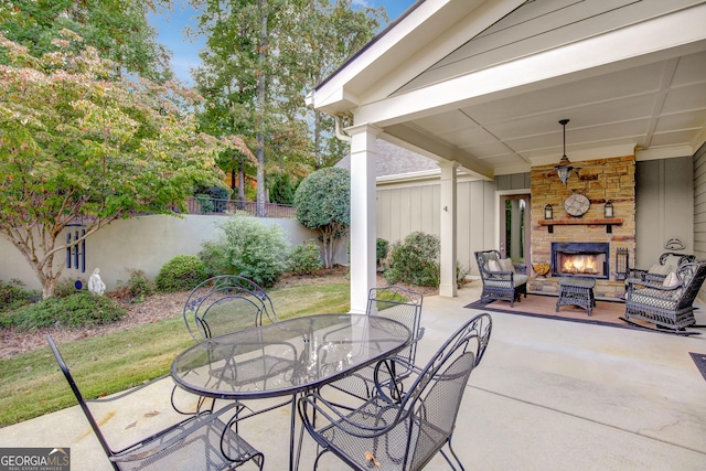 view of patio / terrace featuring fence, outdoor dining space, and an outdoor living space with a fireplace