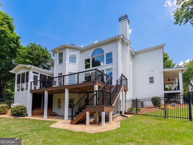 back of house featuring stairs, a sunroom, a ceiling fan, a wooden deck, and a chimney