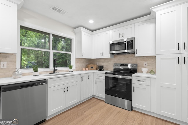 1490 Diplomat Dr, Riverdale, GA 30296 - kitchen featuring appliances with stainless steel finishes, a sink, light countertops, white cabinets, and light wood finished floors