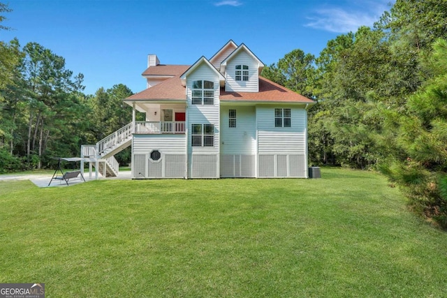 rear view of property with stairs, a yard, a chimney, and central air condition unit