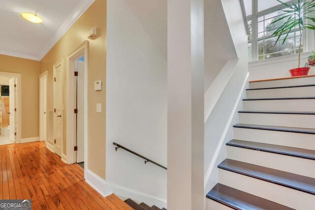 staircase featuring crown molding, wood-type flooring, and baseboards