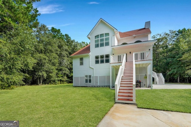 rear view of house with stairs, a chimney, and a lawn