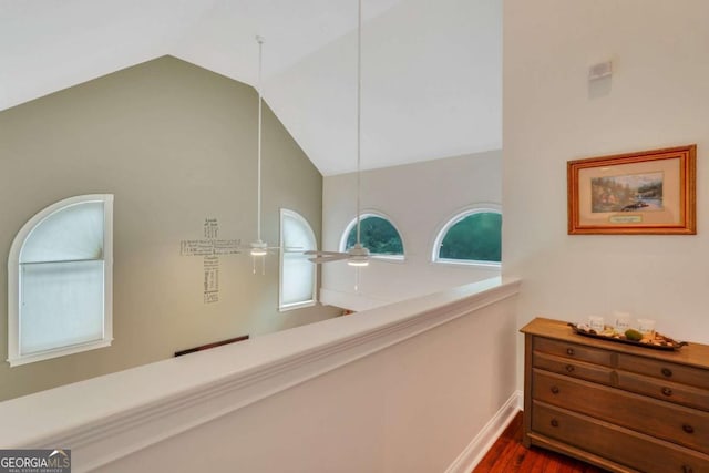 hallway featuring dark wood-style floors, high vaulted ceiling, and baseboards
