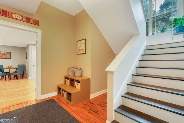 staircase featuring wood finished floors and baseboards