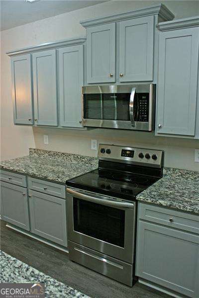131 Queens Cemetery Rd, Good Hope, GA 30641 - kitchen with stainless steel appliances, dark wood finished floors, and stone counters