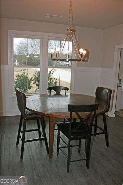 131 Queens Cemetery Rd, Good Hope, GA 30641 - dining area featuring a decorative wall, a chandelier, a wainscoted wall, and dark wood-style flooring