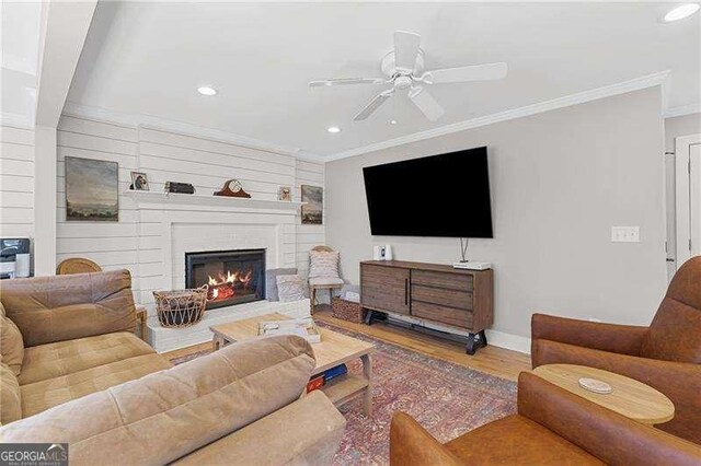 living room with ornamental molding, ceiling fan, recessed lighting, wood finished floors, and a large fireplace