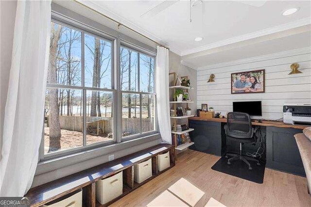 office area with ornamental molding, wood finished floors, and wooden walls