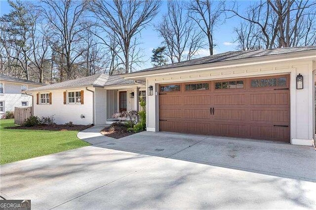 ranch-style home with concrete driveway, an attached garage, a front yard, and stucco siding