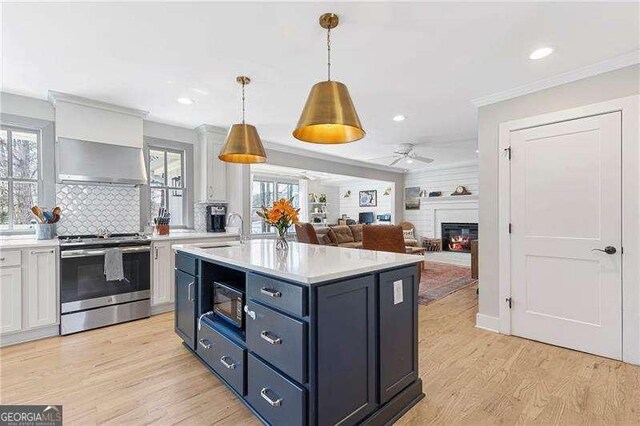 kitchen with stainless steel electric range, a glass covered fireplace, a sink, light countertops, and ornamental molding
