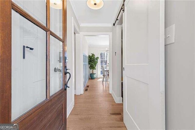 hallway featuring crown molding, light wood-style floors, and baseboards