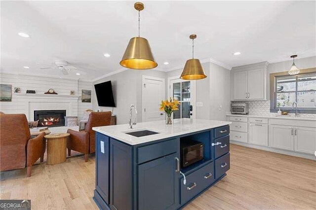 kitchen featuring a sink, blue cabinets, light wood-style floors, recessed lighting, and crown molding