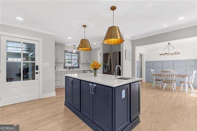 kitchen featuring a sink, stainless steel fridge, light countertops, light wood-style flooring, and a chandelier