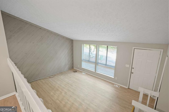 5248 Martins Crossing Rd, Stone Mountain, GA 30088 - unfurnished living room with a textured ceiling, wood finished floors, baseboards, and wood walls