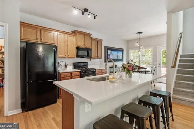 143 Treadstone Ln, Dallas, GA 30132 - kitchen with black appliances, light wood-style floors, light countertops, a kitchen bar, and a kitchen island with sink