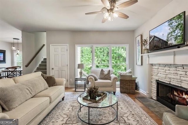 143 Treadstone Ln, Dallas, GA 30132 - living room featuring a stone fireplace, stairway, a ceiling fan, and wood finished floors