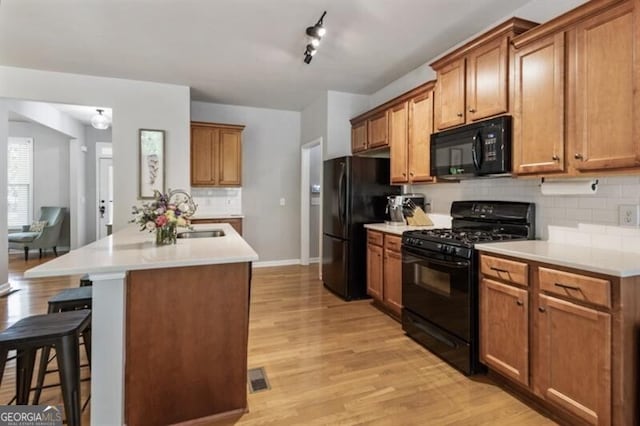 143 Treadstone Ln, Dallas, GA 30132 - kitchen featuring black appliances, a breakfast bar, decorative backsplash, light wood finished floors, and light countertops