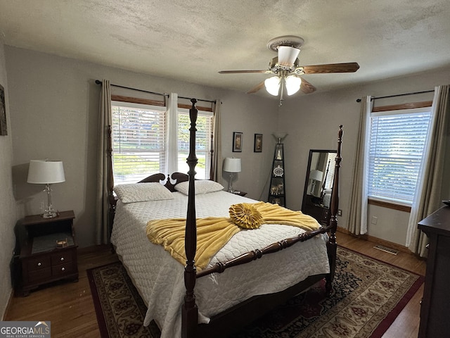 2059 Clearwater Dr SE, Marietta, GA 30067 - bedroom featuring multiple windows, wood finished floors, a textured ceiling, a ceiling fan, and baseboards