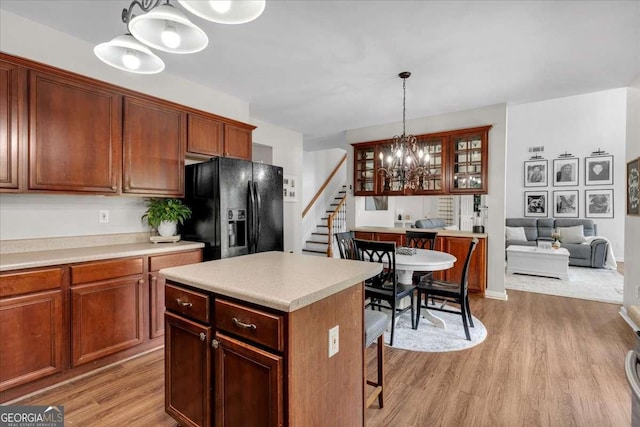 3477 Seneca Farm Dr, Buford, GA 30519 - kitchen featuring black fridge, light wood-style floors, a chandelier, glass insert cabinets, and hanging light fixtures