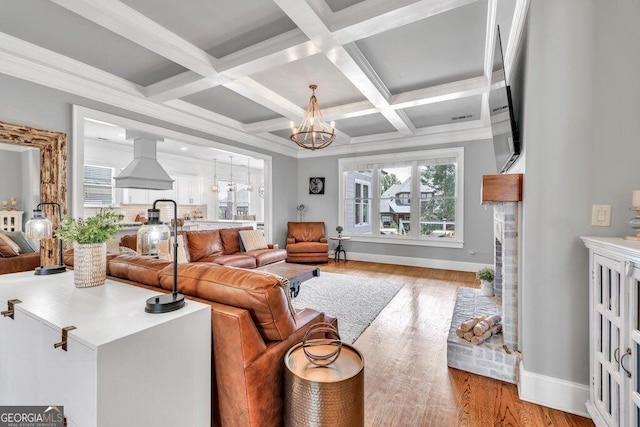 5461 Autumn Flame Dr, Braselton, GA 30517 - living room featuring a chandelier, light wood-style flooring, beam ceiling, baseboards, and crown molding