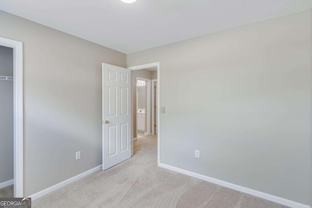unfurnished bedroom with light colored carpet, baseboards, and a closet