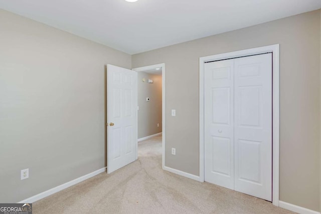unfurnished bedroom featuring light carpet, baseboards, and a closet