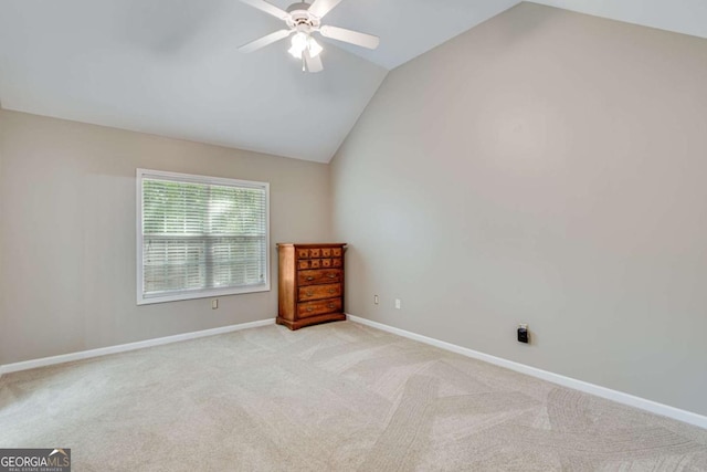 unfurnished room with lofted ceiling, light carpet, a ceiling fan, and baseboards