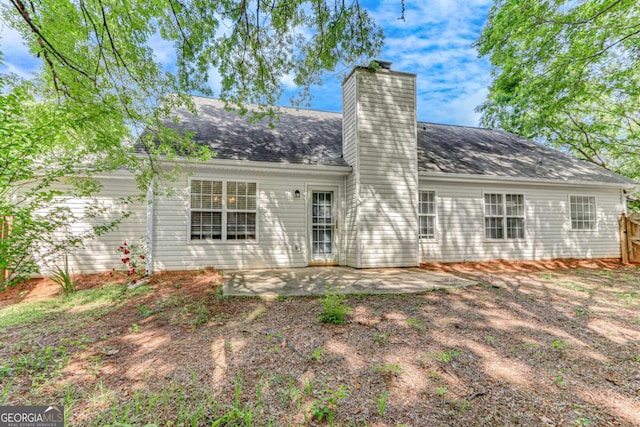 back of house featuring a chimney, a patio area, fence, and a shingled roof
