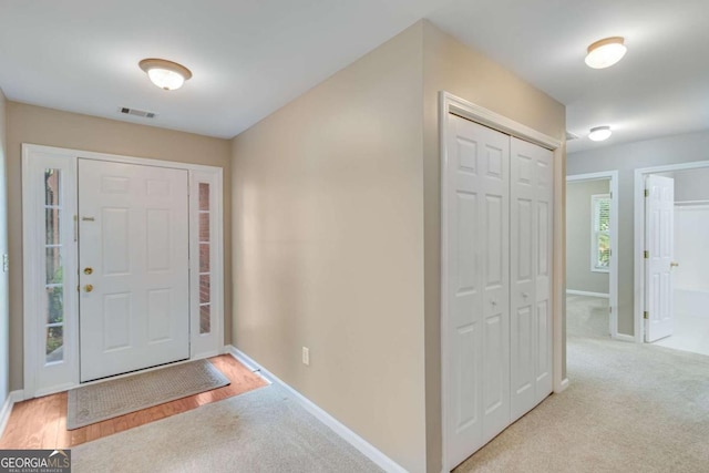 foyer with baseboards and carpet