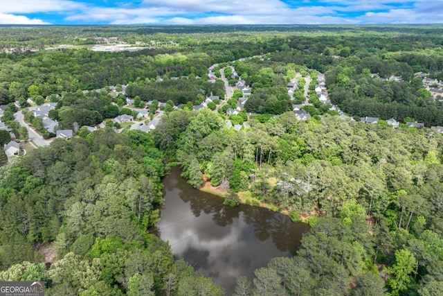 aerial view of property and surrounding area with a forest and a nearby body of water