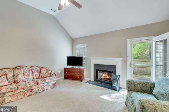 living area with ceiling fan, lofted ceiling, light carpet, a fireplace with flush hearth, and baseboards