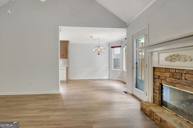 323 Newfield Way, Peachtree City, GA 30269 - unfurnished living room with vaulted ceiling, a chandelier, ornamental molding, a fireplace, and light wood-style flooring