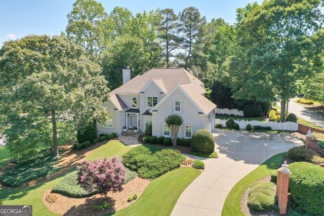 view of front of house with fence, concrete driveway, and a chimney