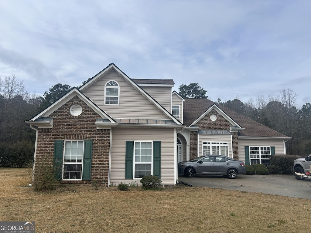 traditional-style house with concrete driveway, a front yard, and brick siding