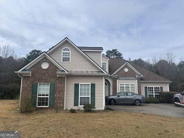 traditional-style house with concrete driveway, a front yard, and brick siding