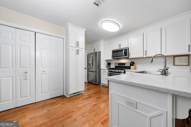 164 Stoneforest Dr, Woodstock, GA 30189 - kitchen featuring stainless steel appliances, white cabinets, decorative backsplash, light stone counters, and light wood-style floors