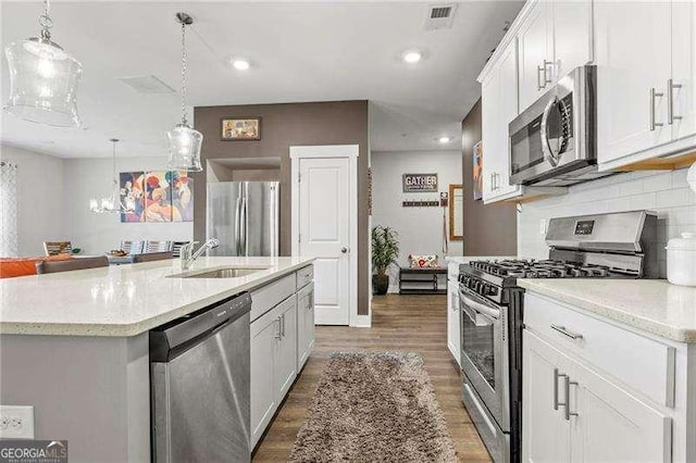 1700 Prospect Way, Conyers, GA 30094 - kitchen with appliances with stainless steel finishes, a sink, light wood-style floors, decorative backsplash, and hanging light fixtures