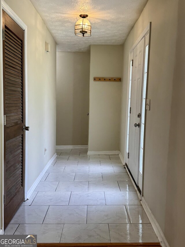 foyer entrance with a textured ceiling and baseboards