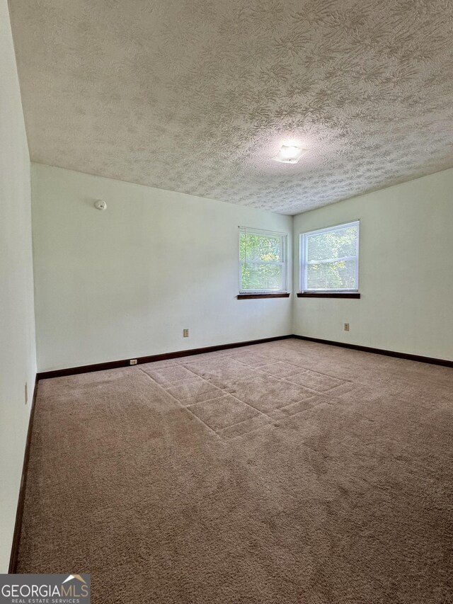 carpeted empty room with a textured ceiling and baseboards