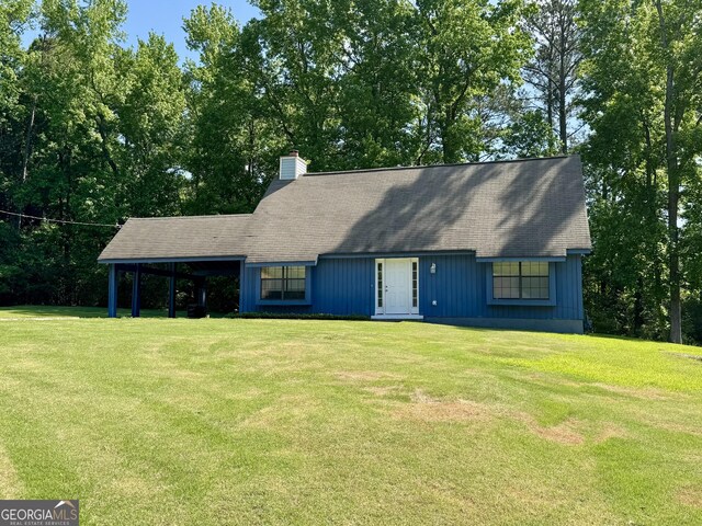 view of front of property with a front yard, a chimney, and an attached carport