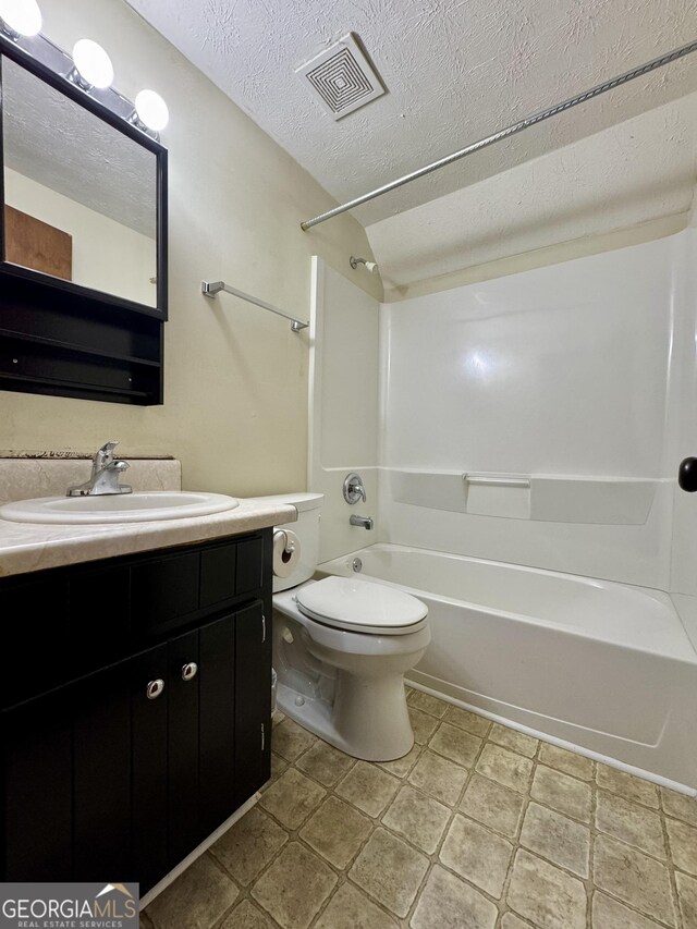 bathroom with toilet, tub / shower combination, vanity, and a textured ceiling