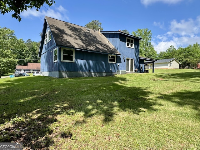 rear view of house with a lawn and roof with shingles