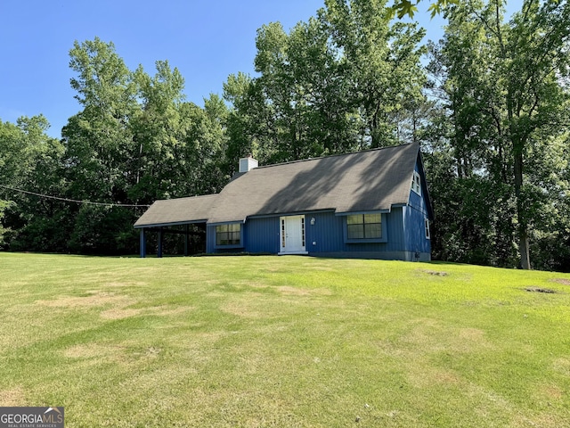 view of front of home with a front yard, a chimney, and an attached carport