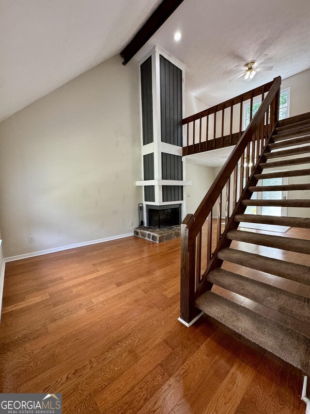 stairway featuring wood finished floors, ceiling fan, baseboards, a stone fireplace, and recessed lighting
